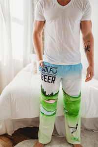 Thumbnail for Male model standing in front of white bed wearing Golf With A Chance Of Beer pajama lounge pants (front view)
