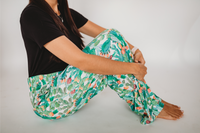 Thumbnail for Waist down photo of model sitting on the floor sideways with knees up wearing Floral Cactus pajama lounge pants