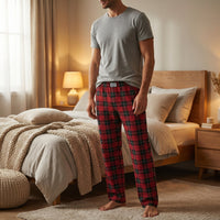 Thumbnail for Male model standing in softly lit bedroom wearing red plaid pajama pants, neutral top, emphasizing comfort and fabric details in a cozy home setting.