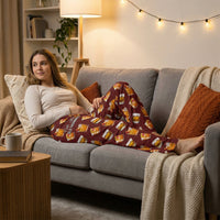 Thumbnail for Relaxed woman lounging on sofa in cozy living room, wearing Old Fashioned Lounge Pants with vivid cocktail print, warm ambient light.
