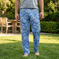 Thumbnail for Female model standing outdoors in a sunny backyard wearing blue hydrangea lounge pants and a neutral t-shirt, relaxed and natural pose, pants clearly visible.