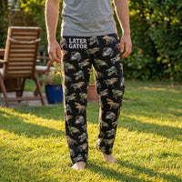 Thumbnail for Male model wearing alligator print lounge pants outdoors in sunny backyard, relaxed and natural pose, pants in focus.