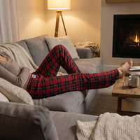 Thumbnail for Model lounging on a modern sofa wearing red plaid pajama pants in a cozy living room scene.