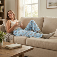 Thumbnail for Person relaxing on sofa in Bugs Bunny lounge pants with all-over print, holding a coffee mug in a cozy living room setting.