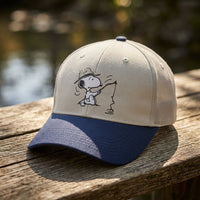 Thumbnail for Close-up of Snoopy Fishing Embroidered Cap showing detailed embroidery and textured fabric on rustic outdoor wooden surface.