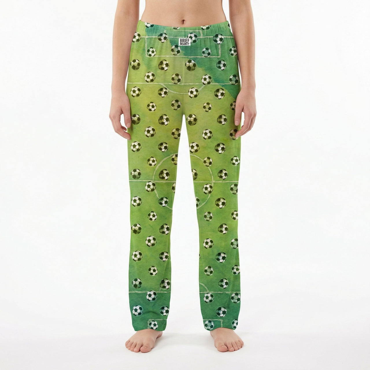 Young female model wearing soccer lounge pants with soccer ball print on white background.