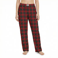 Thumbnail for Young female model standing confidently in a lively living room, wearing red plaid pajama pants, surrounded by plants and playful decor.